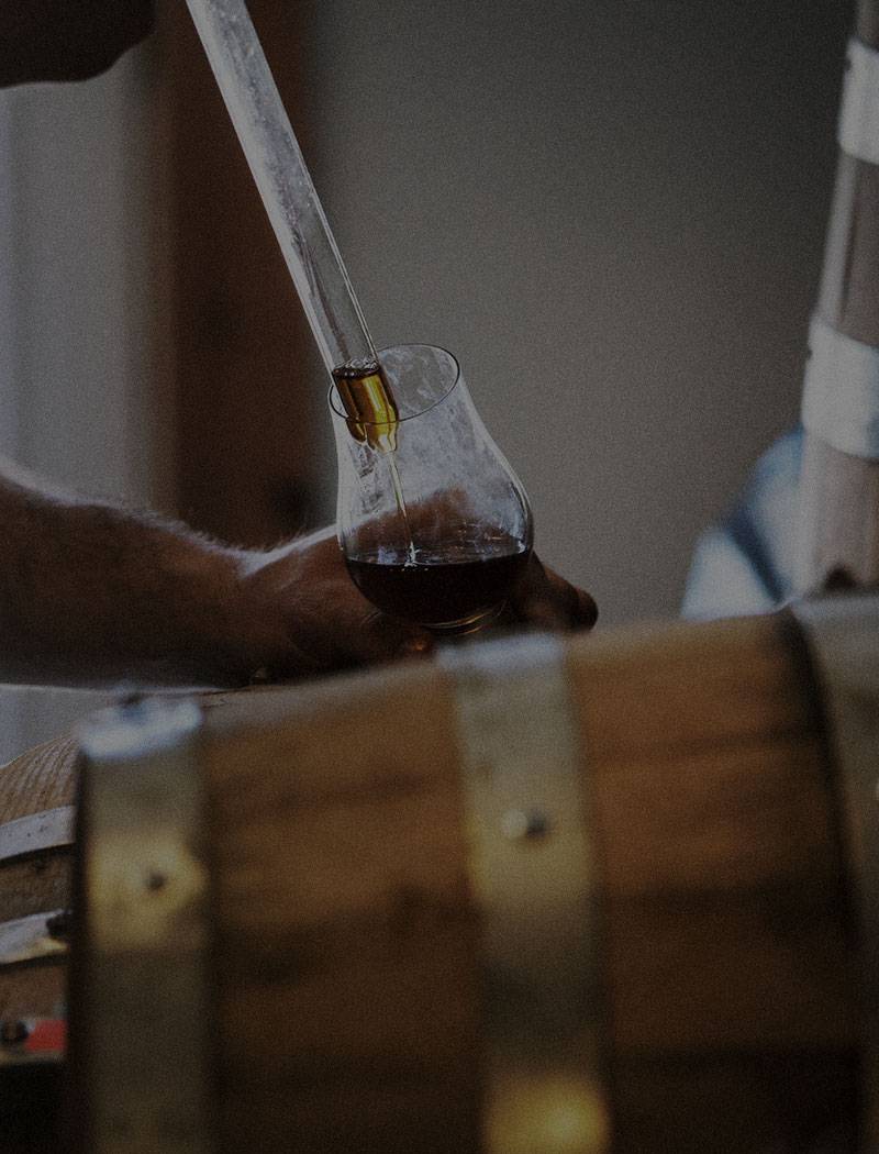 Distiller pulling a sample of Sons of Mitch's Tennessee Whiskey from a barrel